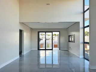 Ambiente interno amplo com piso de concreto polido e portas de vidro.
