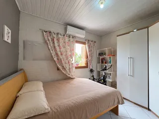 Quarto com cama e armário branco em ambiente de tijolos.