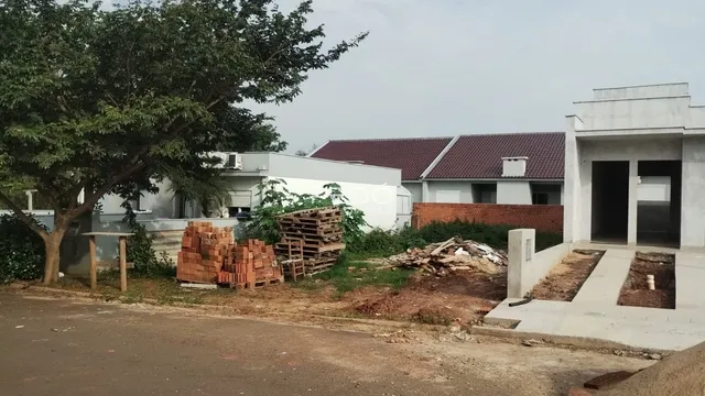 Vista externa de uma propriedade com materiais de construção empilhados na frente.