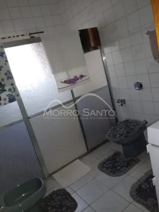 Banheiro com revestimento de azulejos brancos e piso claro.