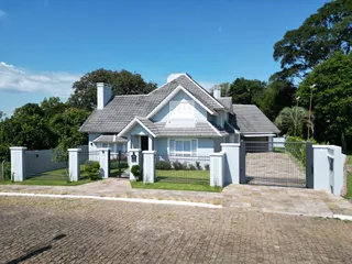 Fachada de uma casa residencial em Lajeado, Brasil, com cerca e paisagismo frontal.