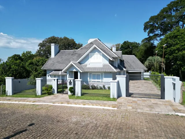 Fachada de uma casa residencial em Lajeado, Brasil, com cerca e paisagismo frontal.