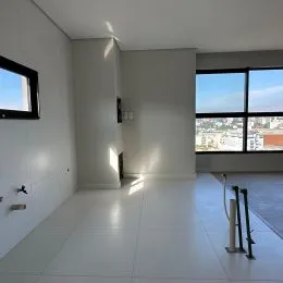 Ambiente interno com paredes brancas e grande janela mostrando a vista urbana.