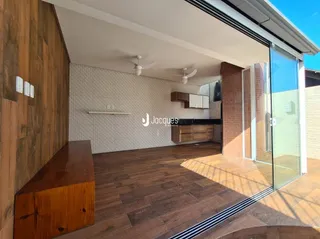 Interior com piso de madeira e porta de vidro que dá para o exterior.