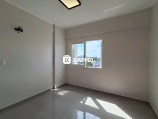Ambiente interno com paredes brancas e piso claro, mostrando uma janela com vista externa.