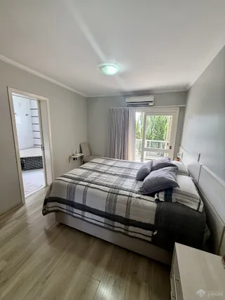 Quarto com piso de madeira e janela com vista para o exterior.