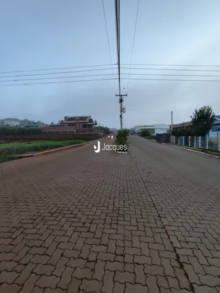 Vista da rua pavimentada em Lajeado, Brasil, com postes de energia.