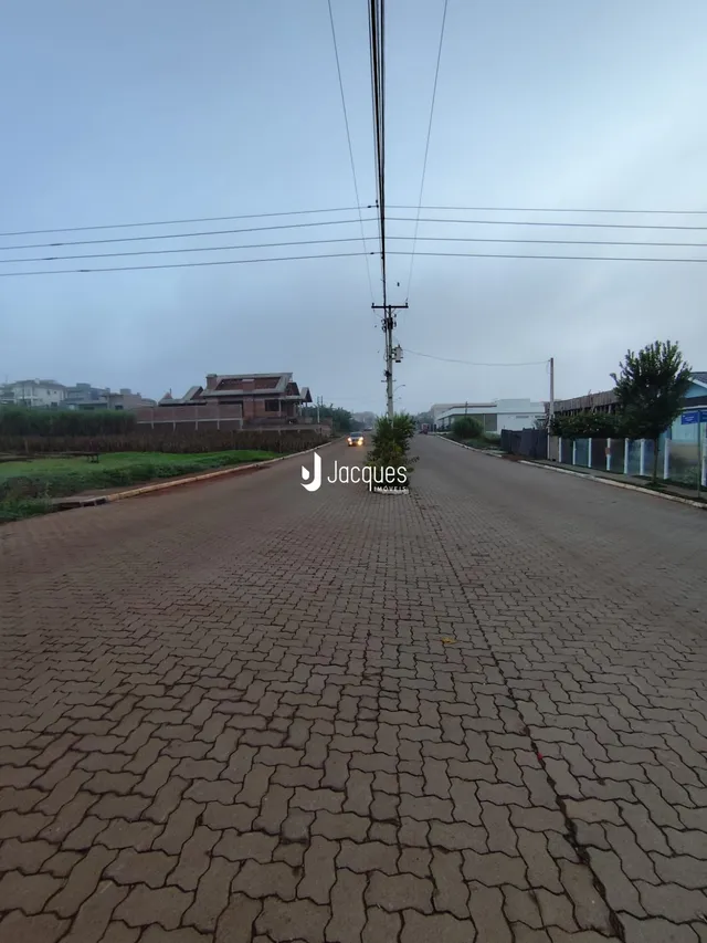 Vista da rua pavimentada em Lajeado, Brasil, com postes de energia.