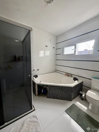 Banheiro com banheira e revestimento de azulejos pretos e brancos.