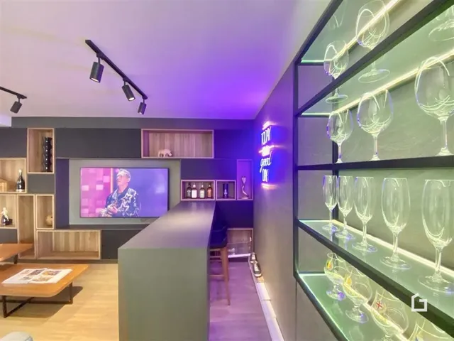 Interior de uma sala de estar moderna com decoração escura e piso de madeira.