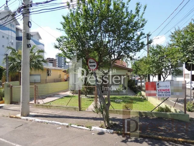 Fachada de uma propriedade residencial com árvores e cerca no jardim.