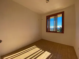 Vista interna de um cômodo com piso de madeira e uma grande janela com vista para o exterior.