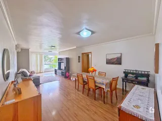 Sala de estar e jantar com piso de madeira clara e móveis de madeira.