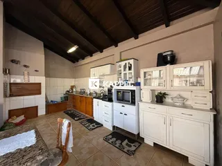 Foto da cozinha com armários brancos e piso de cerâmica.