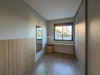 Um corredor interno com piso de madeira e armários embutidos.