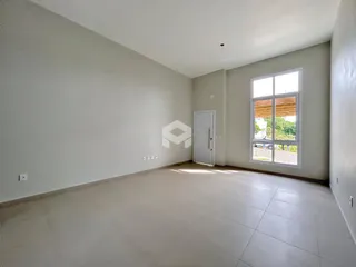 Uma sala de estar ampla com paredes brancas e piso claro.