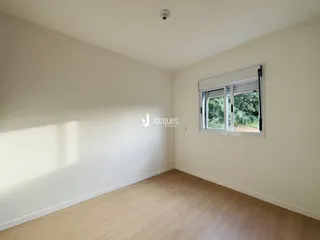 Ambiente interno de uma sala com piso de madeira clara e janela.
