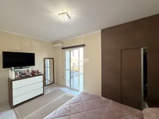 Foto de uma sala de estar com televisão e uma cama em um apartamento.