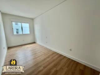 Ambiente interno de uma sala com piso de madeira clara e paredes brancas.