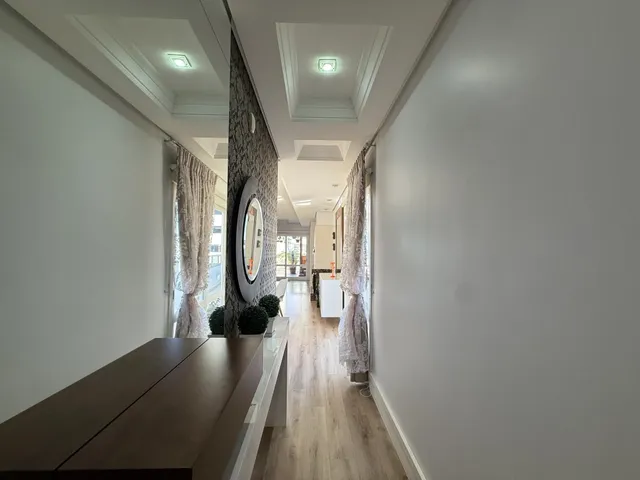 Hall de entrada com paredes brancas e piso de madeira clara.