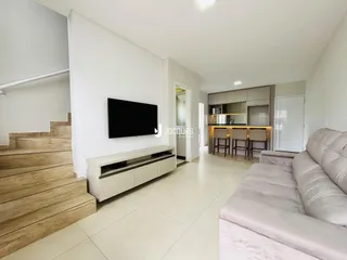 Sala de estar com cozinha integrada e escadaria de madeira.
