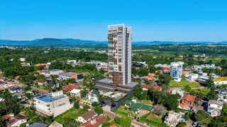 Vista aérea de uma área residencial em Lajeado, Brasil, mostrando casas e um edifício alto.