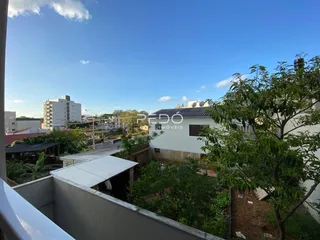 Vista externa de uma residência branca com jardim e vegetação.