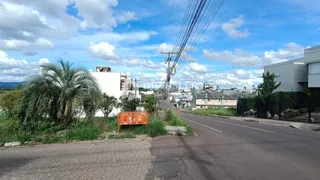 Vista externa de uma rua residencial em Lajeado, Brasil com vegetação e edificações ao fundo.