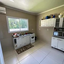 Cozinha com armários brancos e piso de cerâmica.