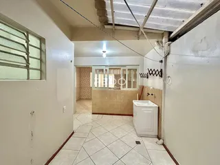 Corredor interno com piso de cerâmica claro e teto de estrutura exposta.