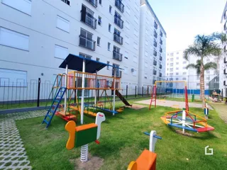 Área externa com gramado e equipamentos de playground.