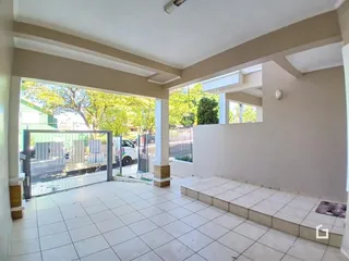 A foto mostra uma área externa com piso de cerâmica e uma abertura para o jardim.