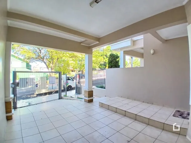 A foto mostra uma área externa com piso de cerâmica e uma abertura para o jardim.