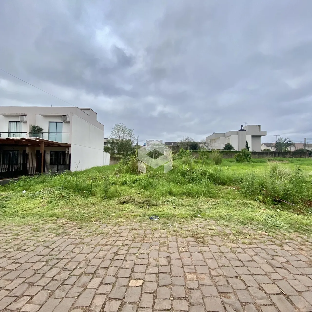Vista da fachada de uma residência com área gramada e pavimento em primeiro plano.
