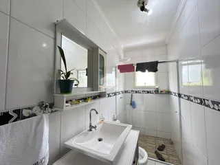 Banheiro com revestimento branco e piso de cerâmica.