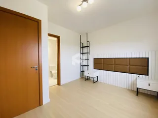 Quarto com piso de madeira clara e parede de destaque.