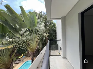 Vista da varanda com piscina e vegetação tropical.