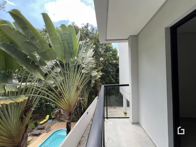 Vista da varanda com piscina e vegetação tropical.