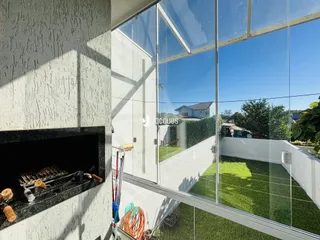 Vista da fachada de uma casa com grandes portas de vidro que dão para um jardim gramado.