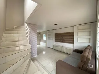 Sala de estar com escadaria e piso de cerâmica clara.
