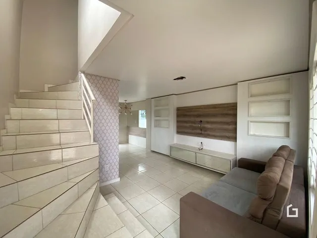 Sala de estar com escadaria e piso de cerâmica clara.