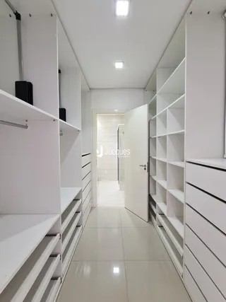 Corredor interno com estantes brancas em um imóvel.