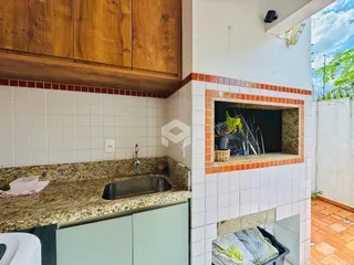 Foto de uma cozinha com armários de madeira e revestimento de azulejos brancos.