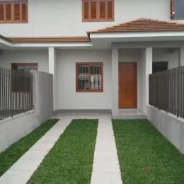 Vista de um pátio externo com gramado e calçadas claras.