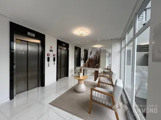 Hall de entrada com piso de porcelanato claro e iluminação bem distribuída.