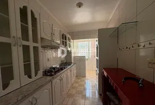 Vista da cozinha com armários brancos e piso de cerâmica.