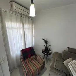 Foto de um cômodo interno com janelas cobertas por cortinas brancas.