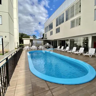 Piscina externa com espreguiçadeiras ao lado de um prédio moderno.