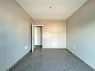 Vista interna de um corredor com paredes cinzas e piso de concreto.