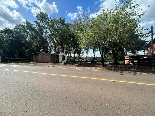 Vista da propriedade ao longo de uma estrada com vegetação e cerca.